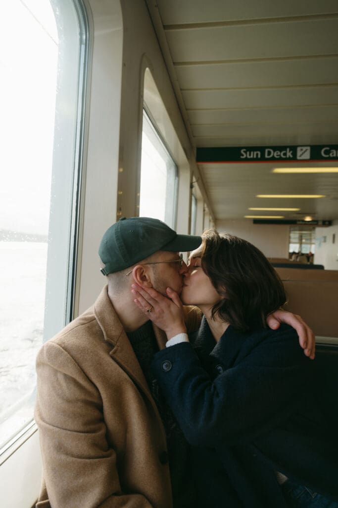 A couple sitting together kissing in the booth of a Seattle ferry