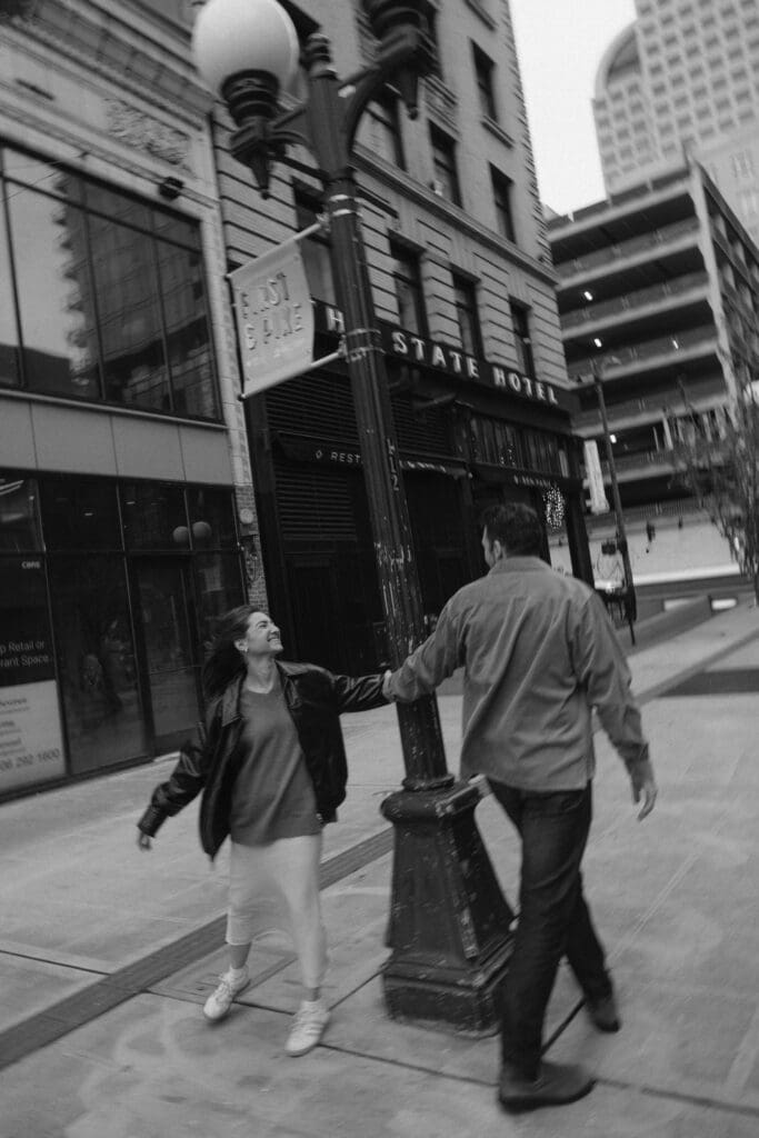 Blurry black and white photo of a couple running around a light post in the city