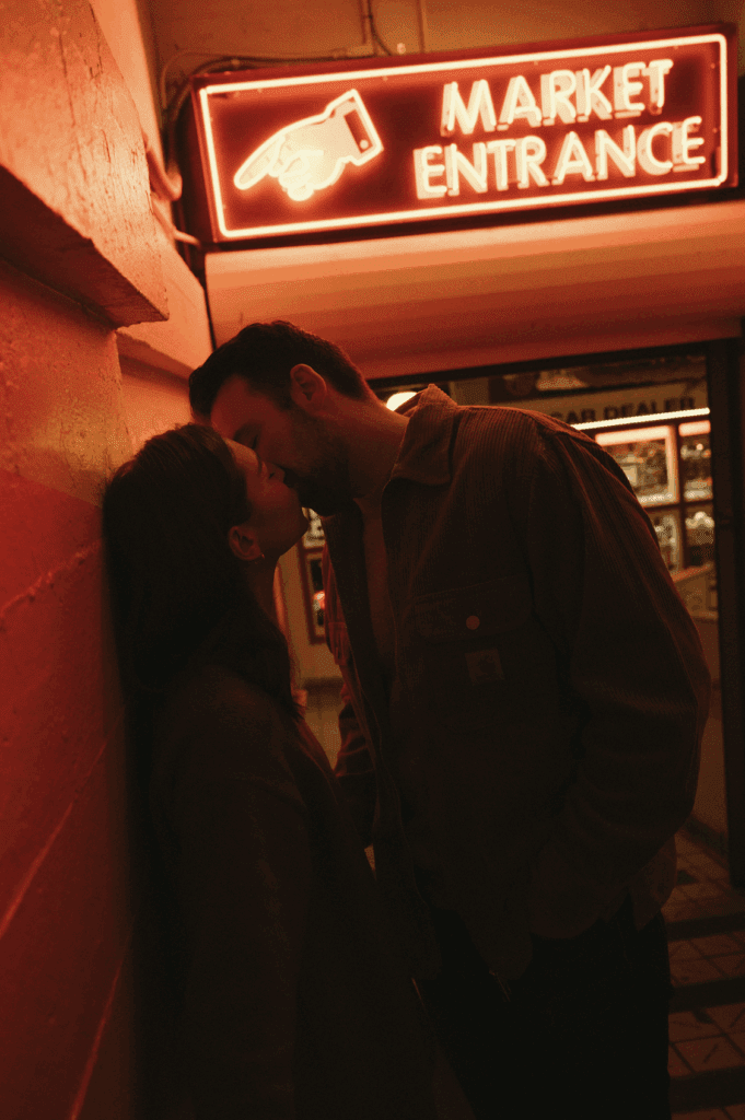 Couple kissing under the red neon sign of Pike Place Market