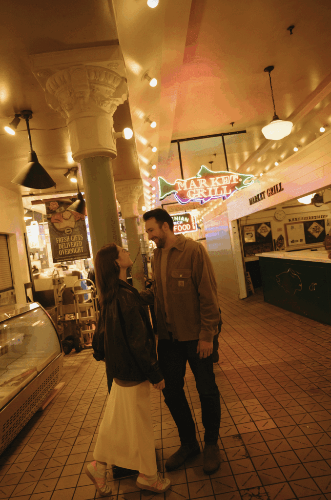Couple facing each other under the neon lights in Pike Place Market