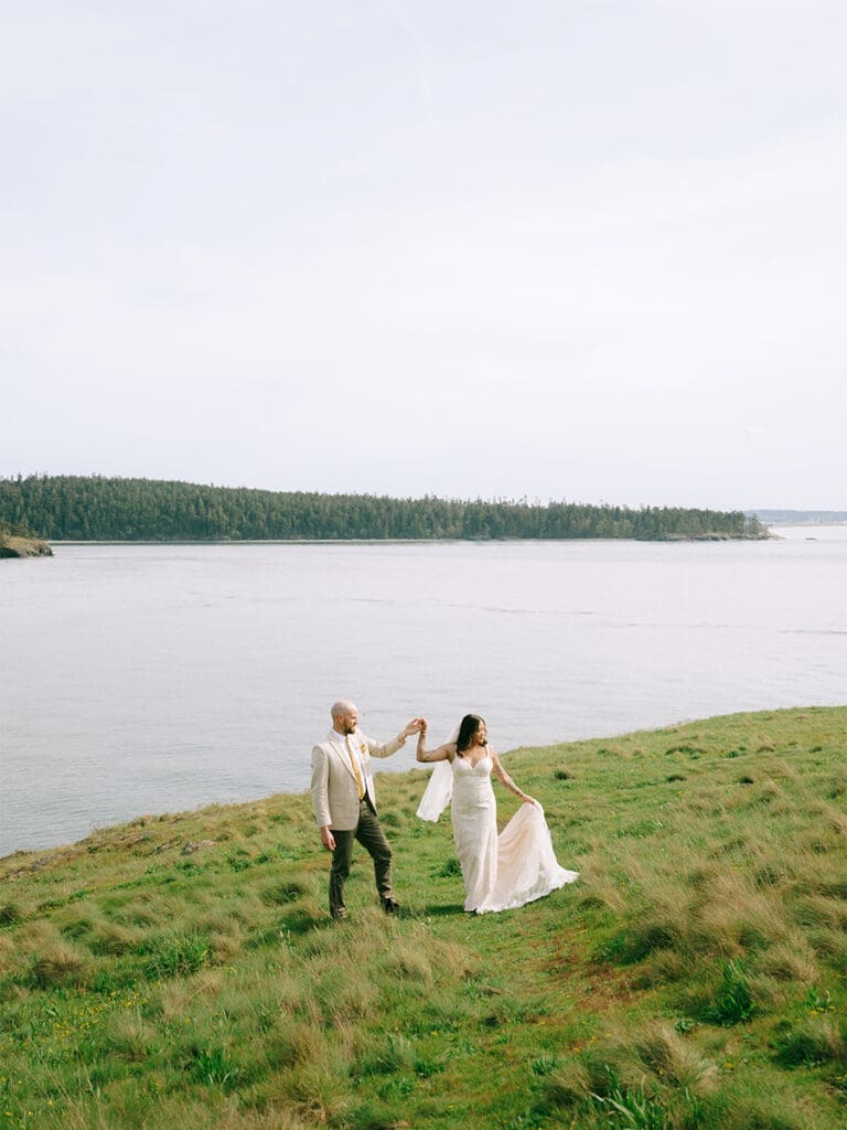 Couple in wedding attire standing on green cliffs at their Deception Pass Elopement
