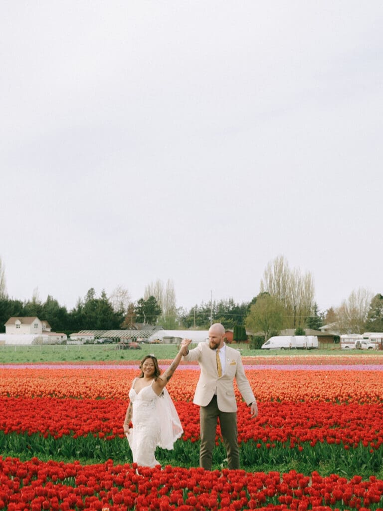 A couple in wedding attire twirling in the Skagit Valley Tulip Fields