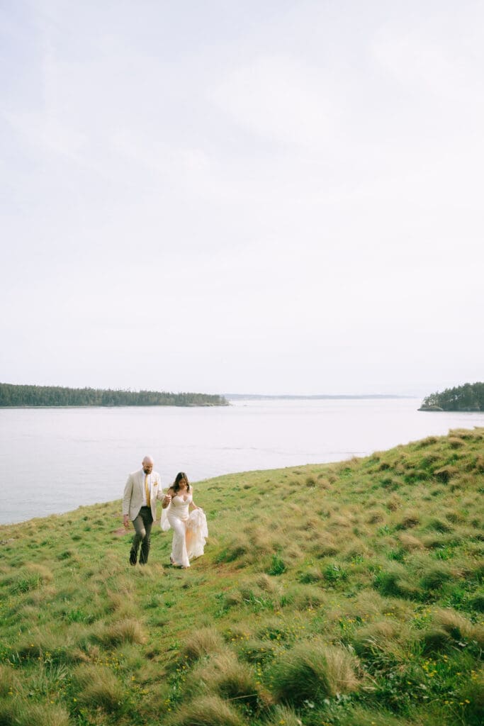 Couple in wedding attire standing on green cliffs at their Deception Pass Elopement