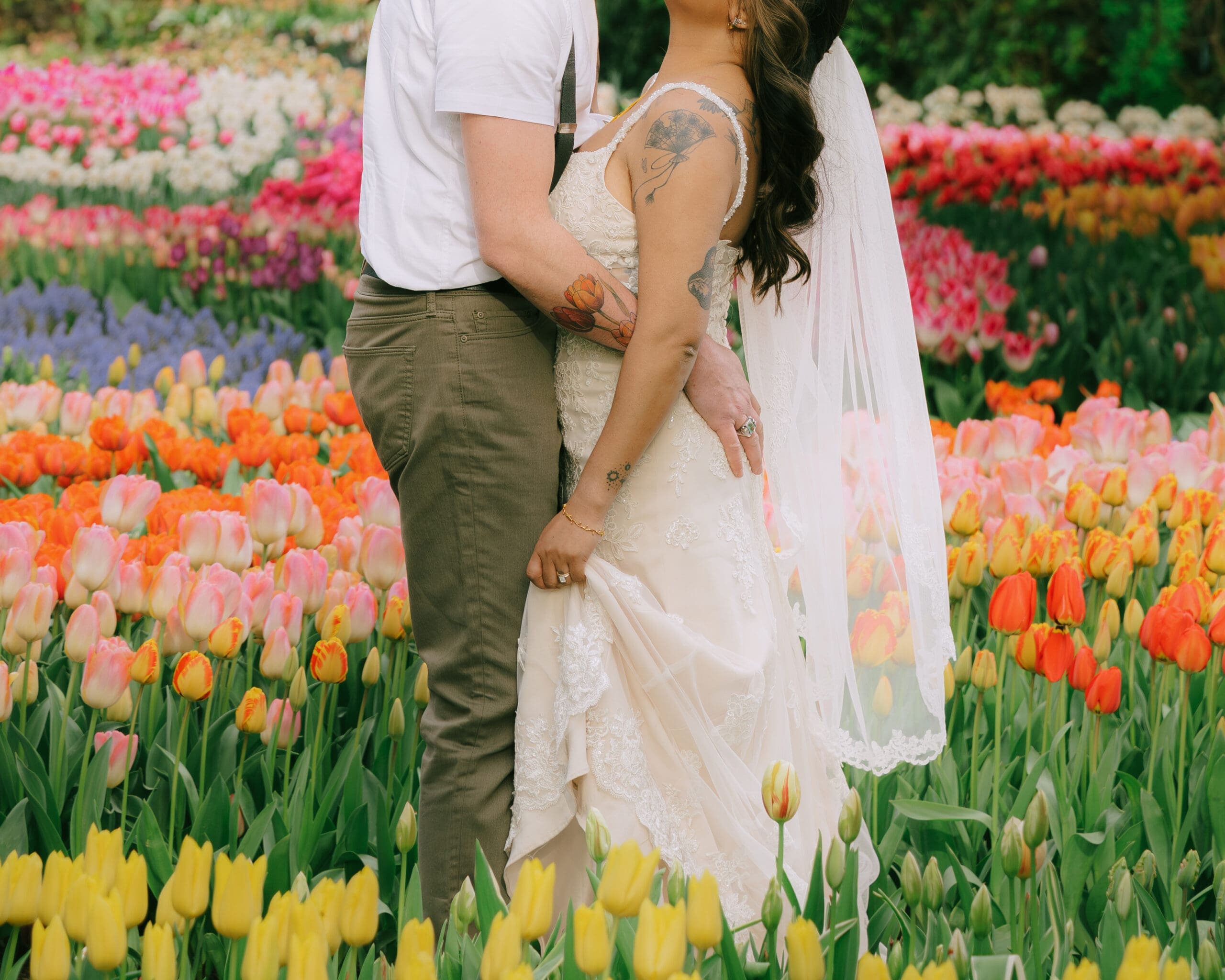 Photo of a couple in wedding attire kissing in a colorful tulip field