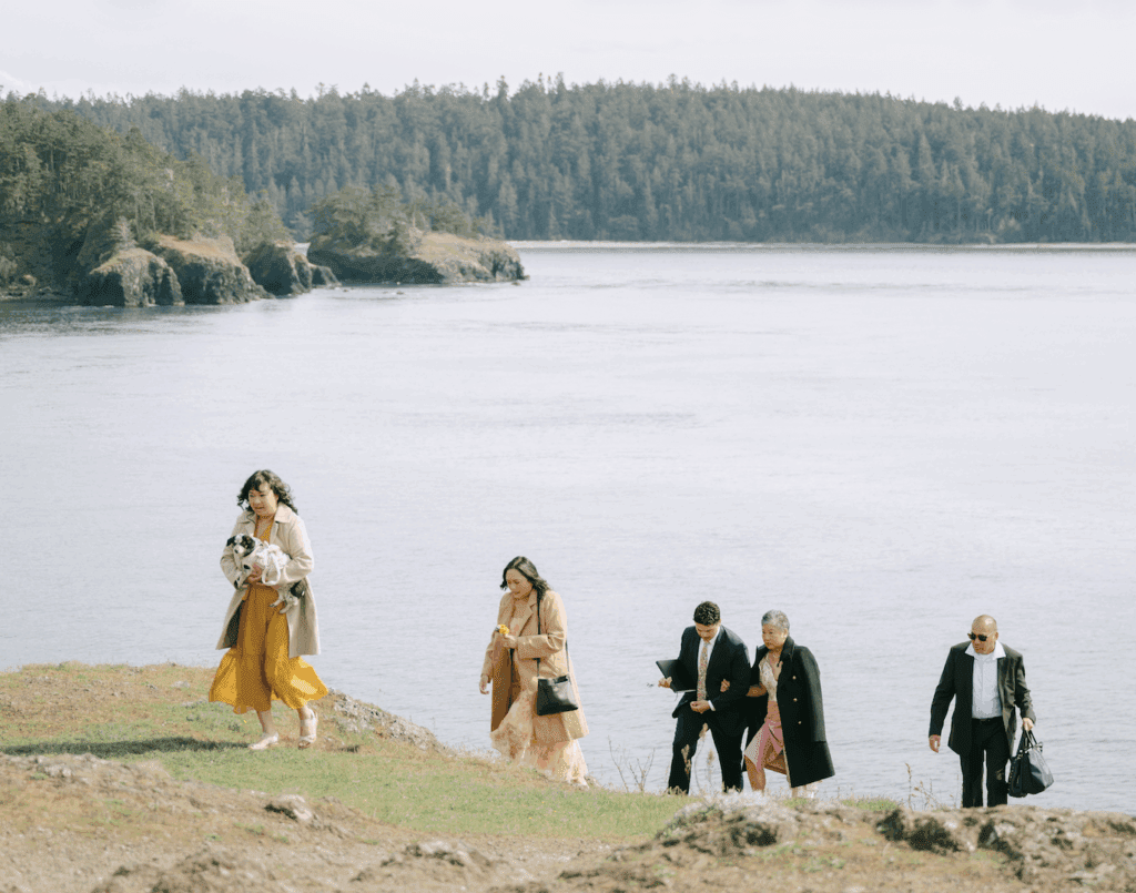 A couple in wedding attire and their families standing on cliffs above water at their Deception Pass elopement